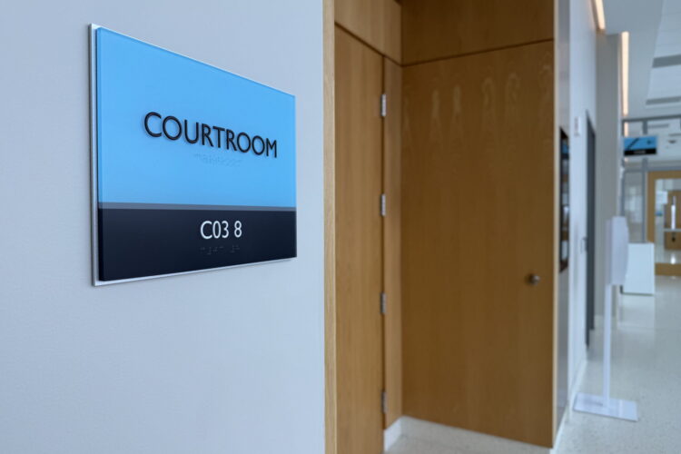 A hallway outside an Indiana courtroom, with a blue sign labeled "Courtroom" on the wall.