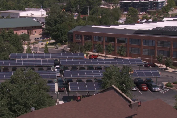 An aerial rooftop view showing several solar panels atop carports near professional buildings.