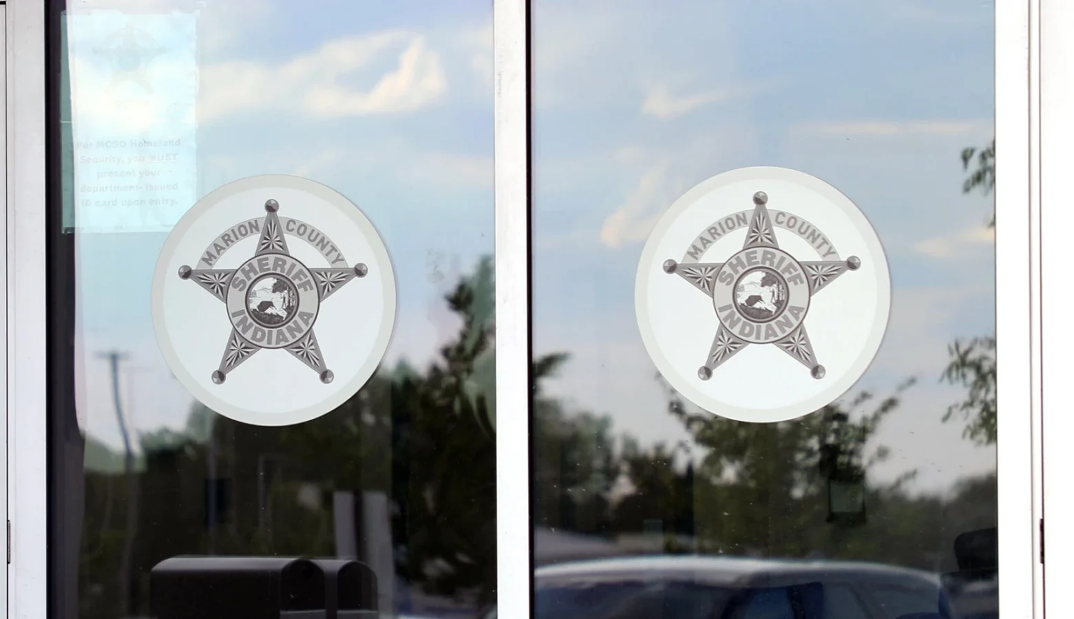 Two windows display dinner-plate sized Marion County Sheriff star logo. The photo is shot from the out of doors.
