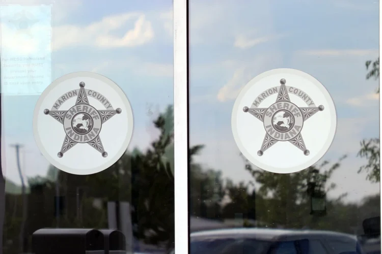 Two windows display dinner-plate sized Marion County Sheriff star logo. The photo is shot from the out of doors.