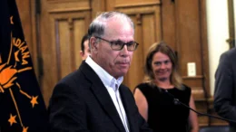 Governor Mike Braun is pictured in his office, with the Indiana flag behind him.