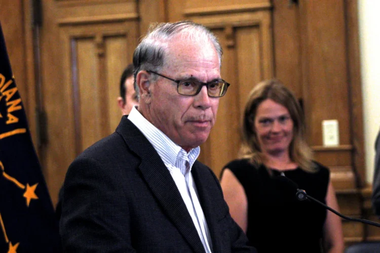 Governor Mike Braun is pictured in his office, with the Indiana flag behind him.