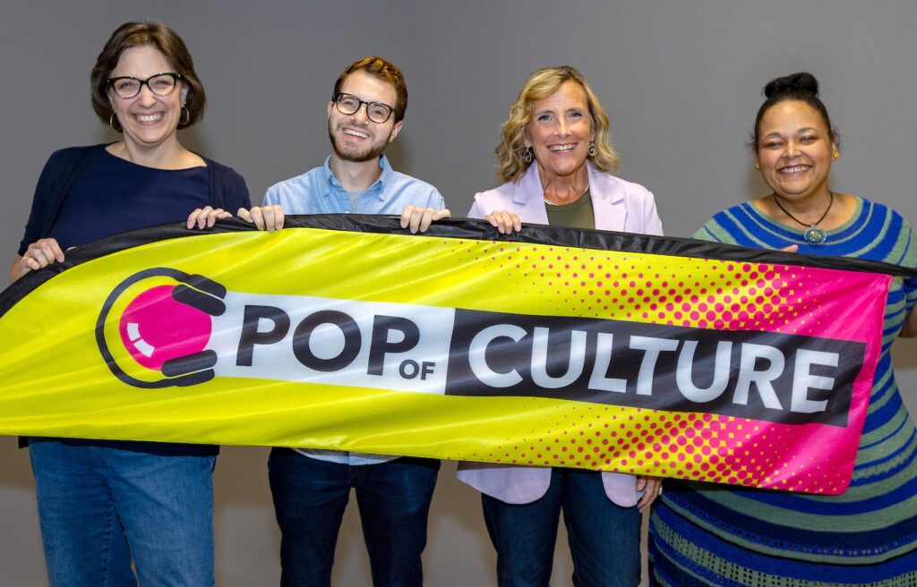 The Pop of Culture team holding a banner with the Pop of Culture logo
