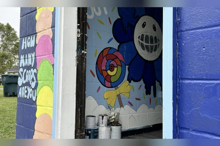 A building with an open door showcases hand-painted murals of ice cream cones and happy flowers and candy.