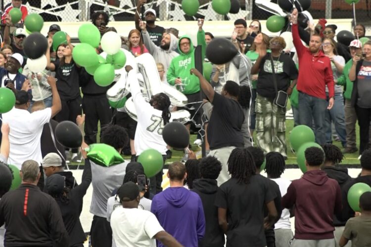A crowd of people release green balloons at a prayer vigil.
