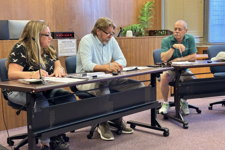 The Floyd County Election Board held an emergency meeting Friday, Oct. 9, 2026, after discovering hundreds of incomplete ballots issued to voters. Three members of the board, a woman and two men, are seated at a table in a wood-paneled meeting chamber with papers in front of them.