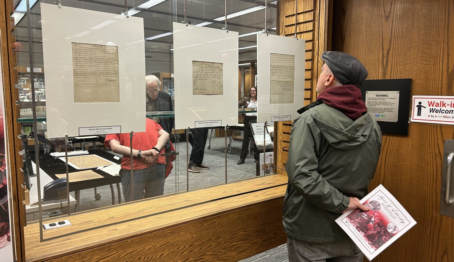 A person stands looking at historic documents hung on a display at Ball State's Bracken Library.