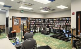 A room in a library includes bookshelves, desks, and chairs.