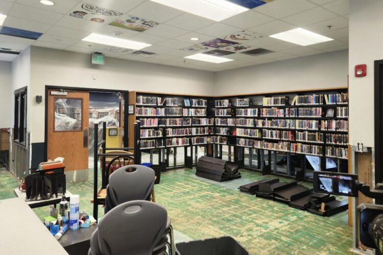 A room in a library includes bookshelves, desks, and chairs.